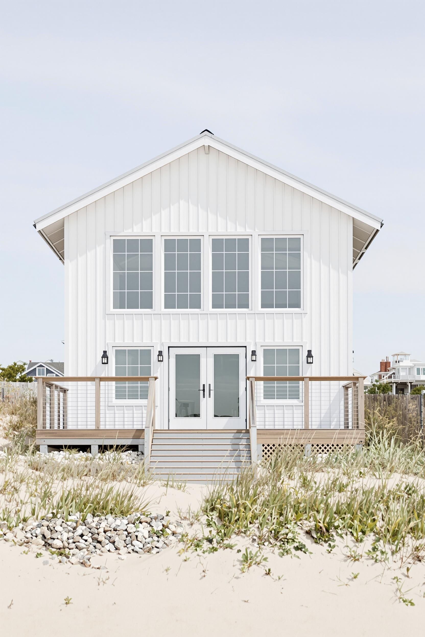 White beach house with large windows and sandy path