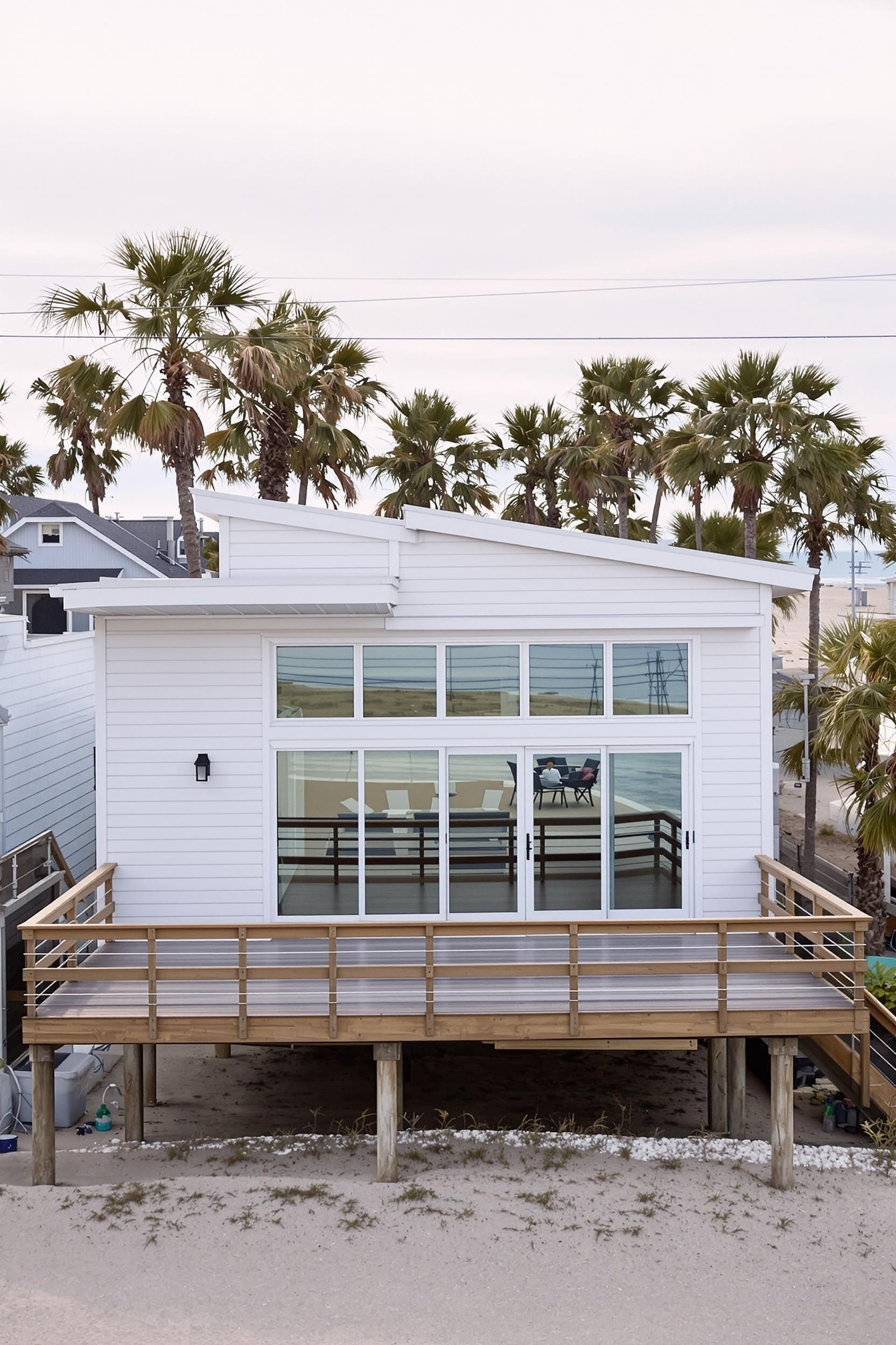 Small white beach house with large windows and a wooden deck