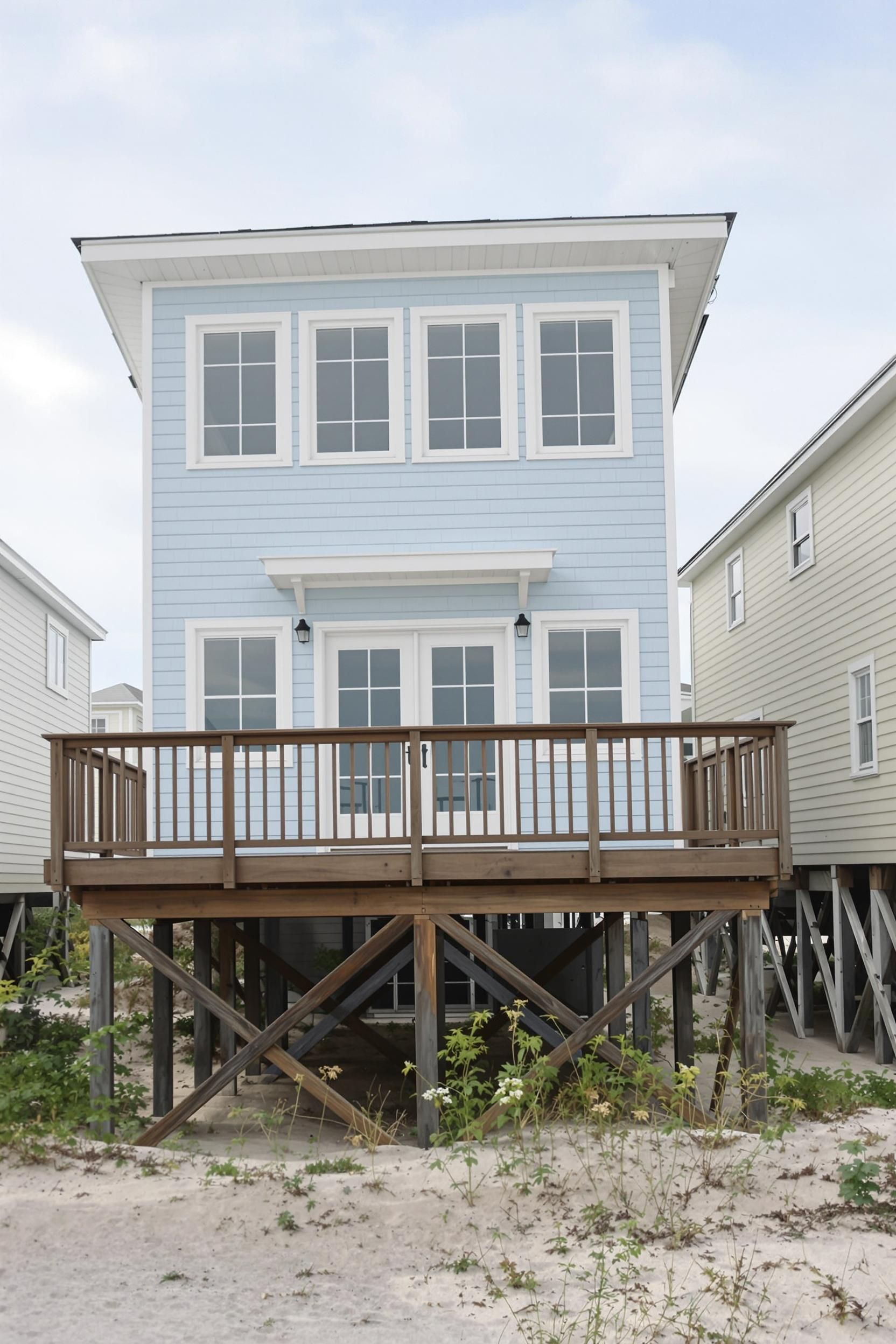 Beachfront house with a light blue facade and wooden deck