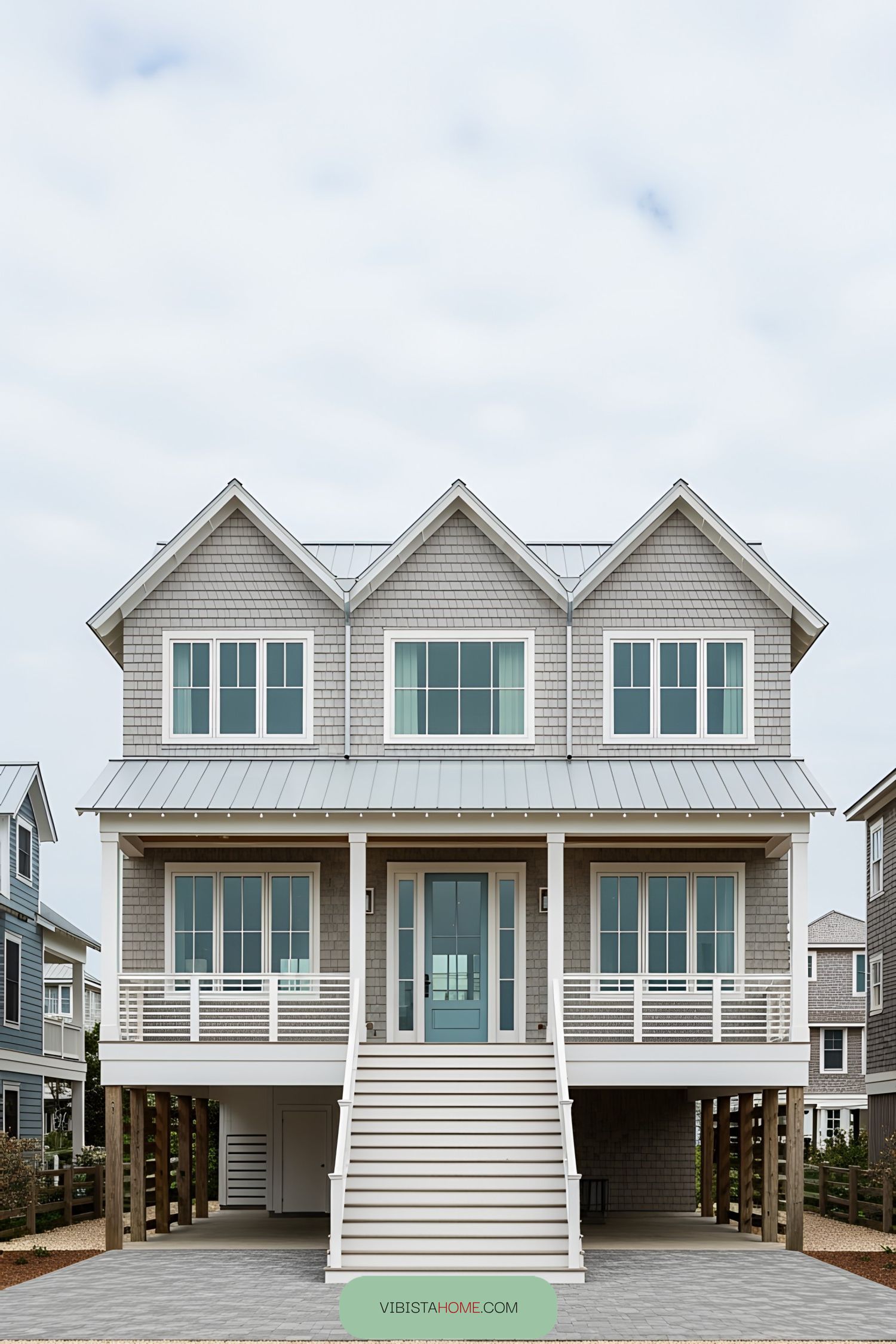 Beach house on stilts with large windows and stairs