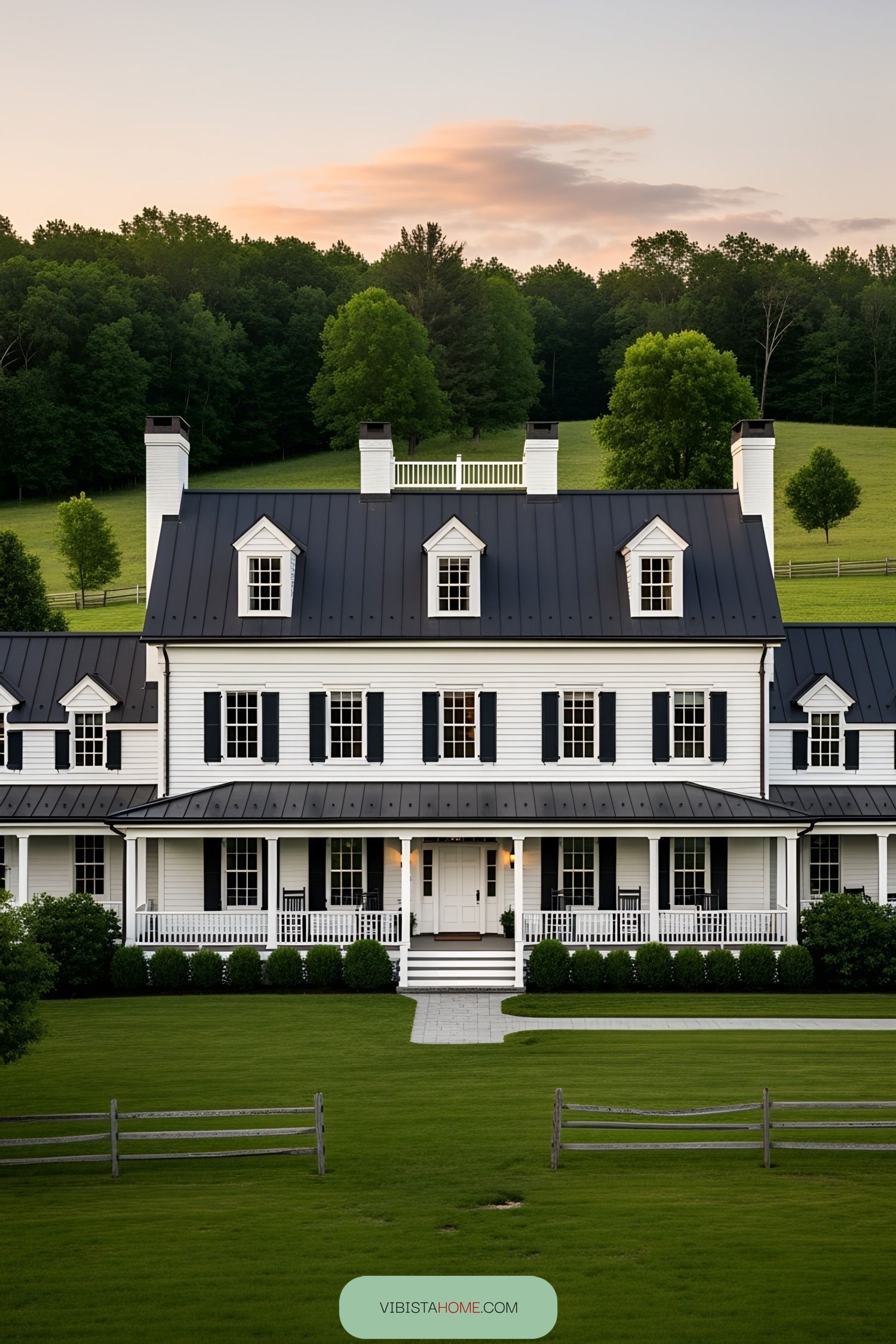 White barn house with dark roof amidst lush greenery