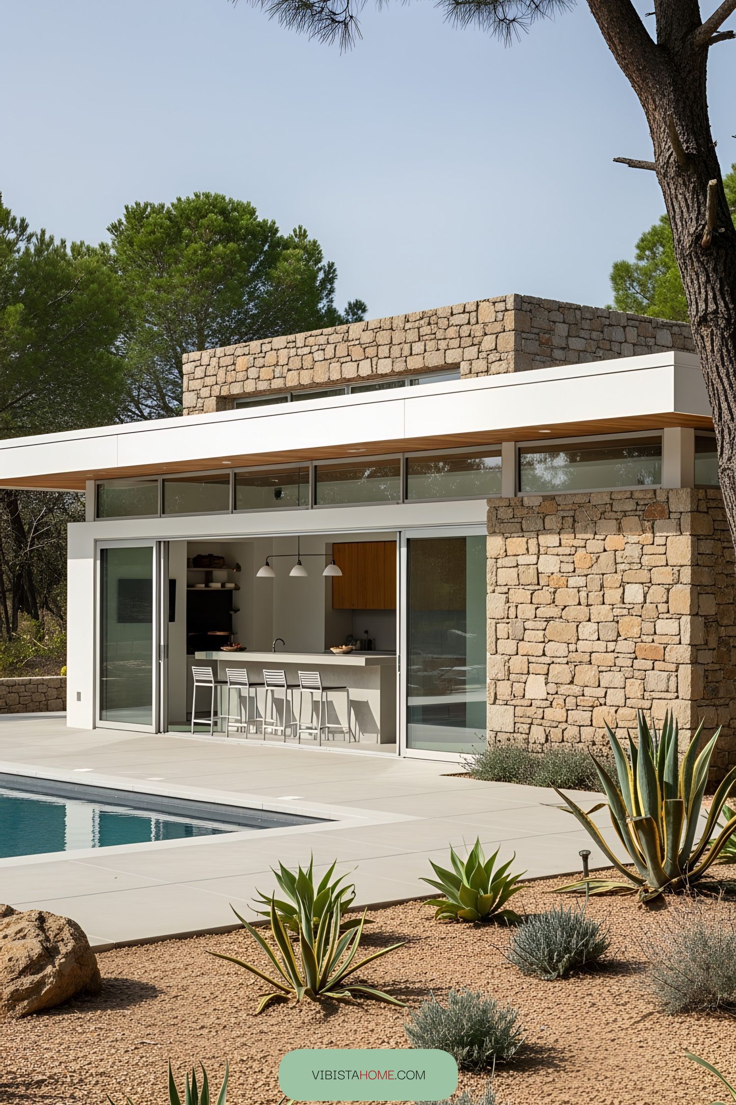 Modern pool house with stone walls and floor-to-ceiling windows