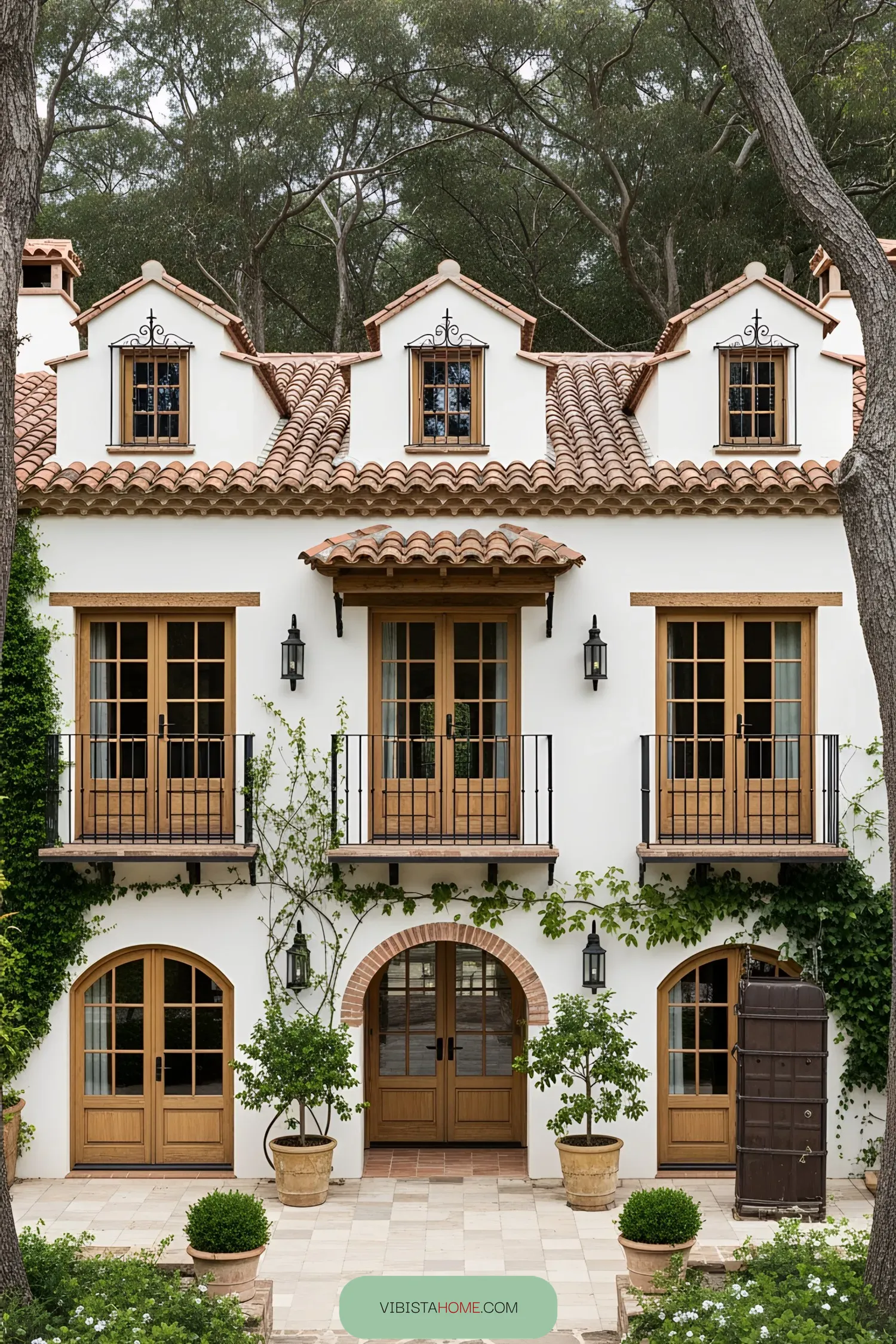 Facade of a classic Spanish farmhouse with large wooden doors and lush greenery