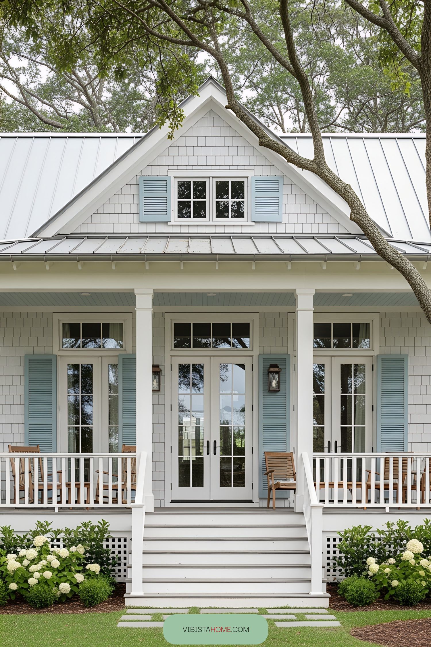 White bungalow with blue shutters and lush greenery