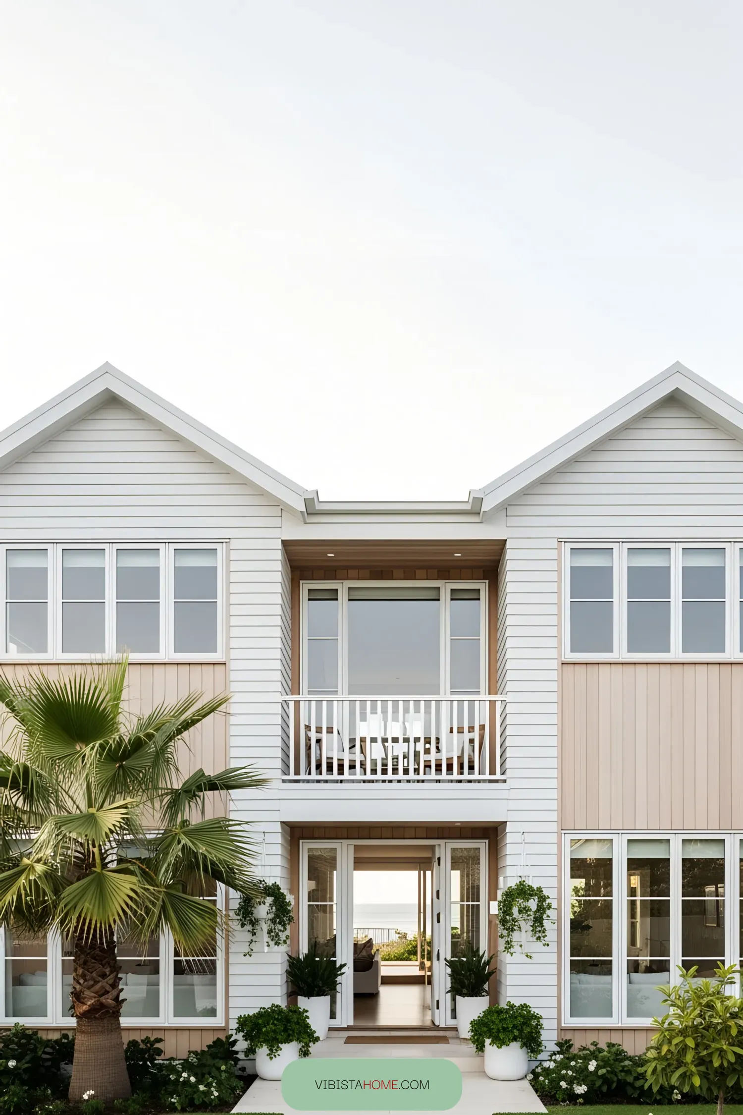 Modern coastal house with palm tree and expansive windows