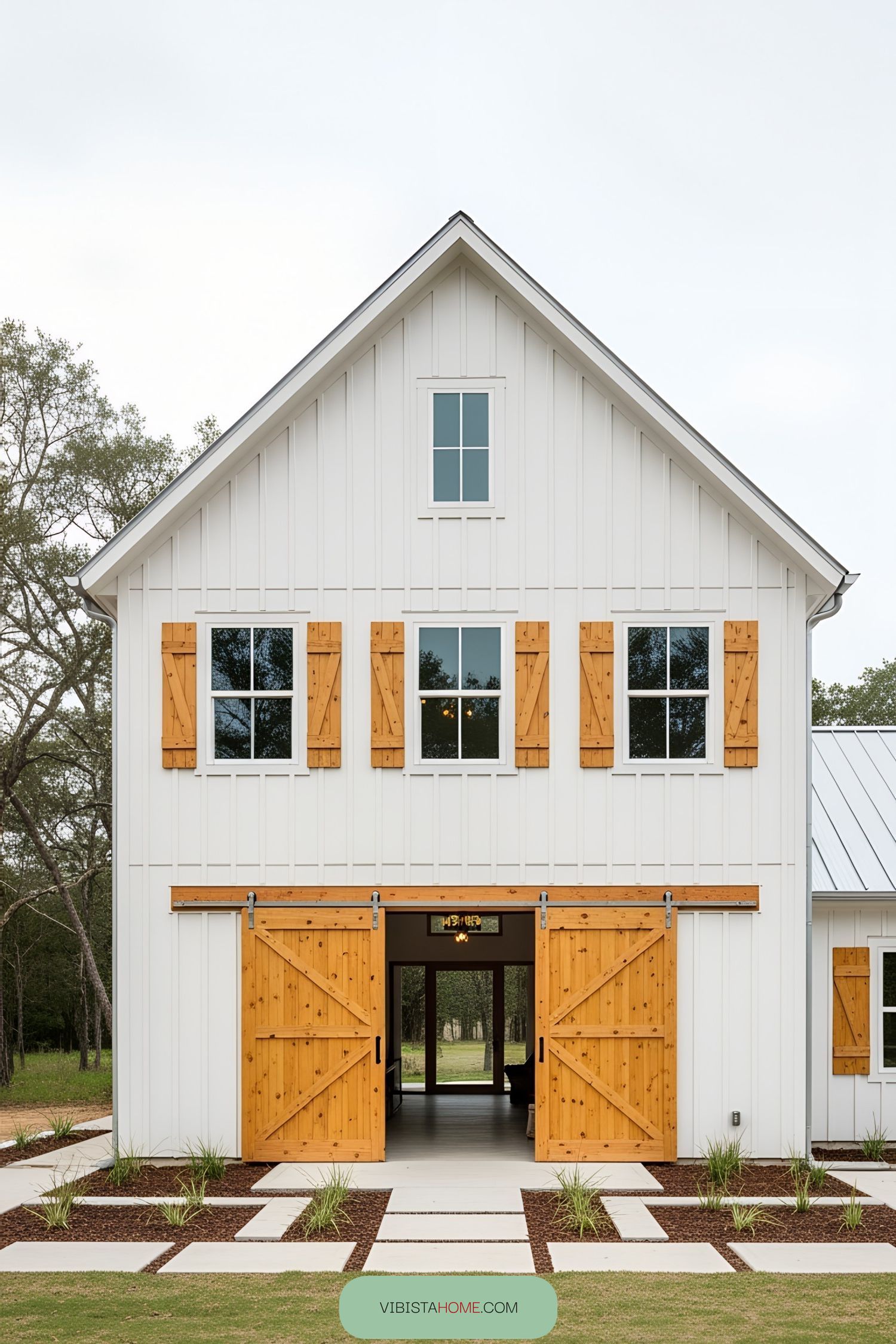 White barn house with large wooden doors and a gabled roof
