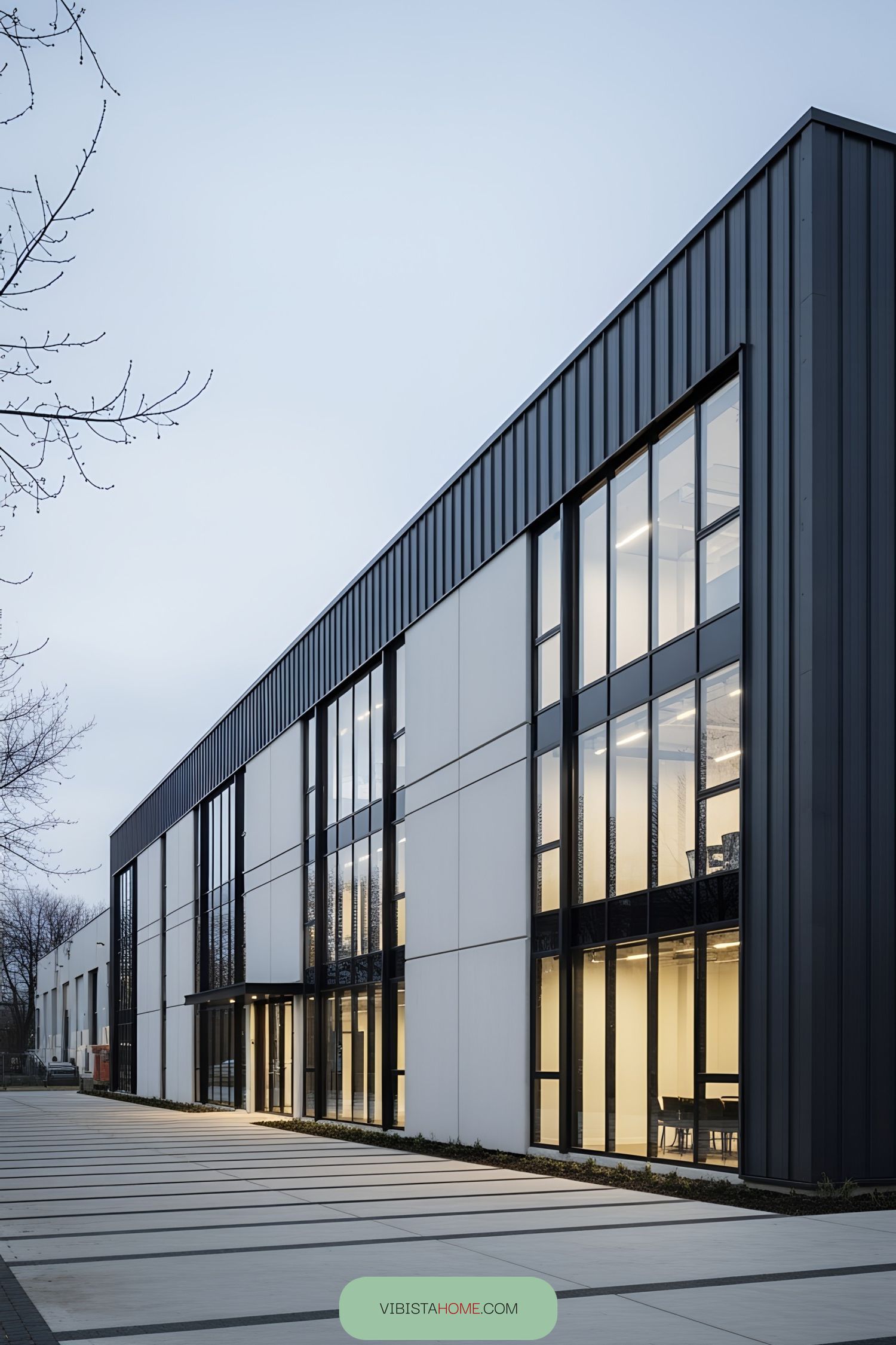 Modern industrial building with a sleek facade, featuring large vertical windows and a combination of dark panels and light surfaces