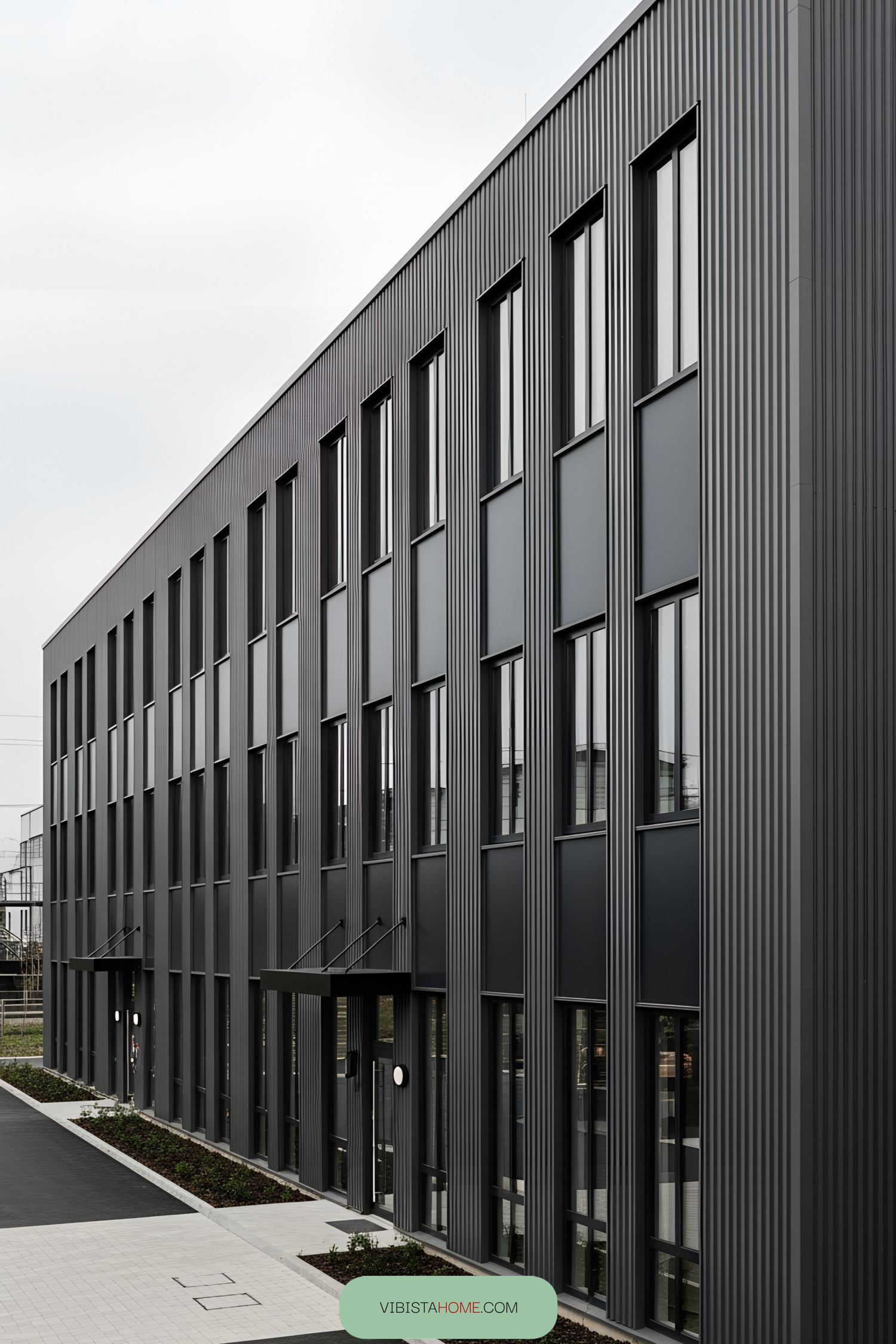 Modern industrial building with tall, sleek windows and ridged metal facade