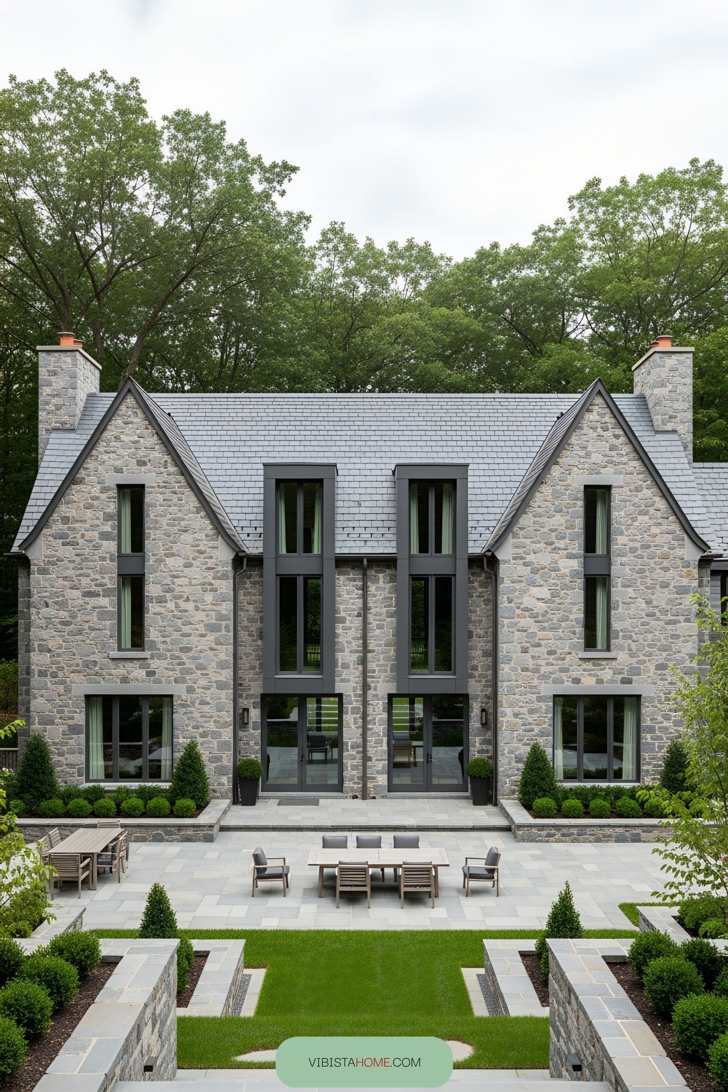 Front of a stone house with large windows and a symmetrical design