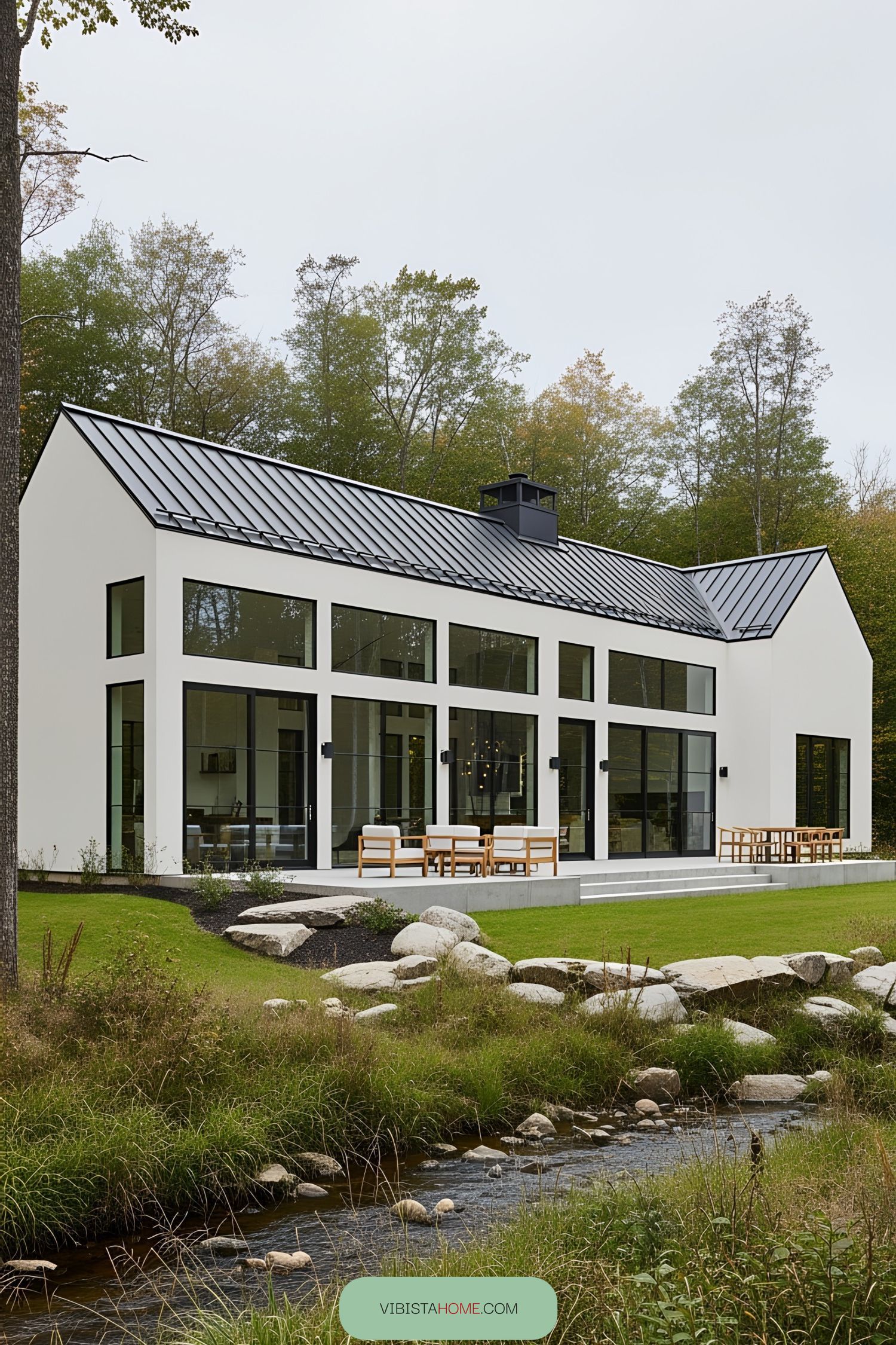 Modern Scandinavian farmhouse with glass facade and lush surroundings by a stream