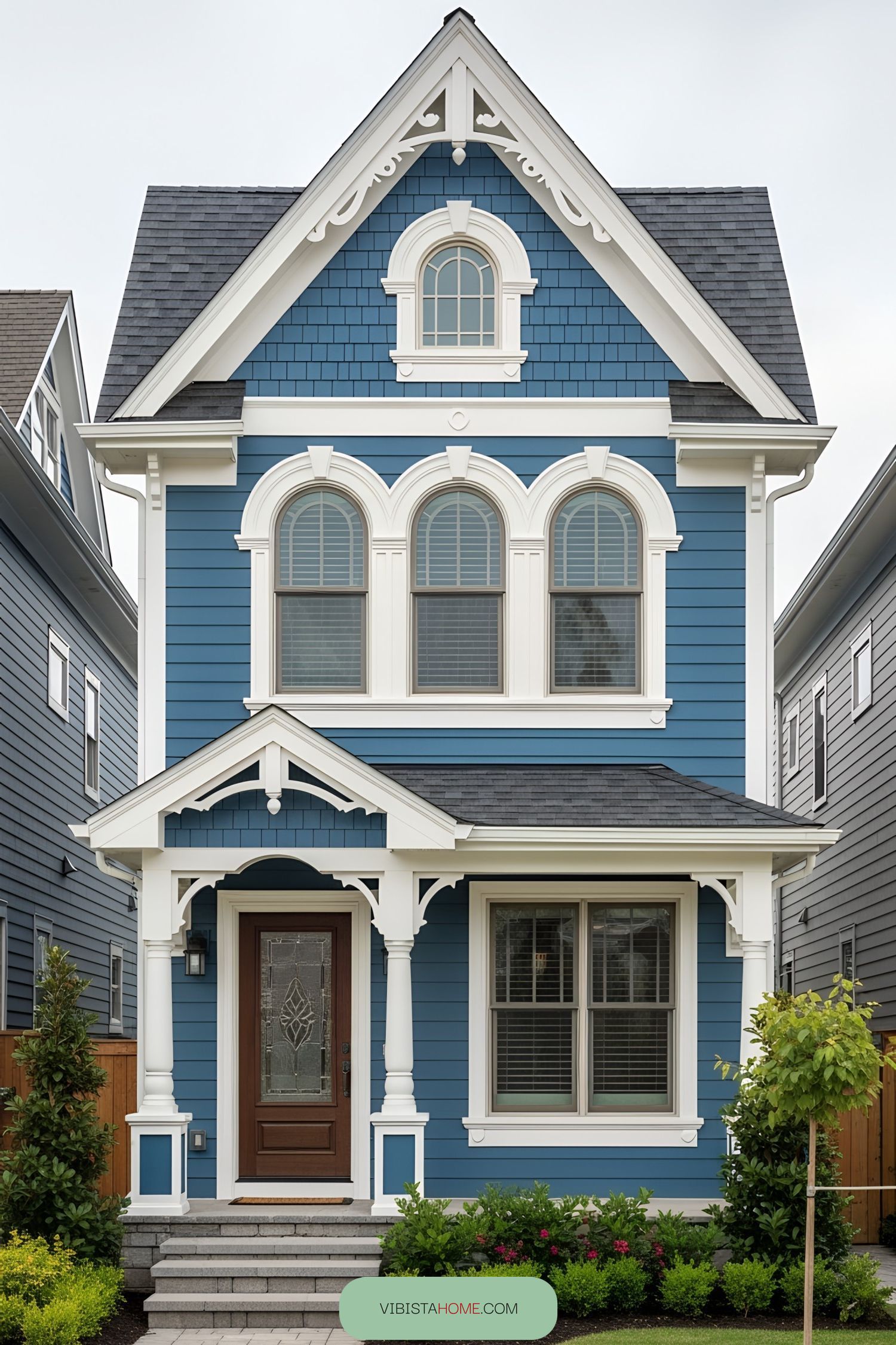 Blue Victorian tiny house with white trim and arched windows