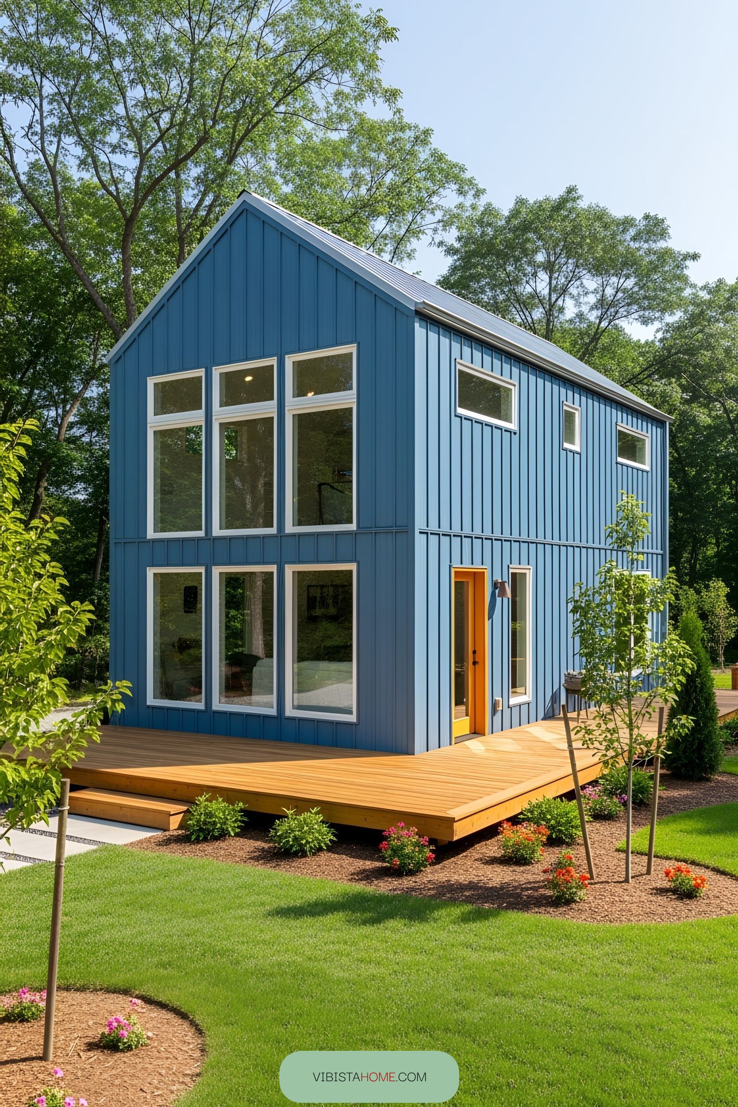 Compact blue barndominium with a wooden deck