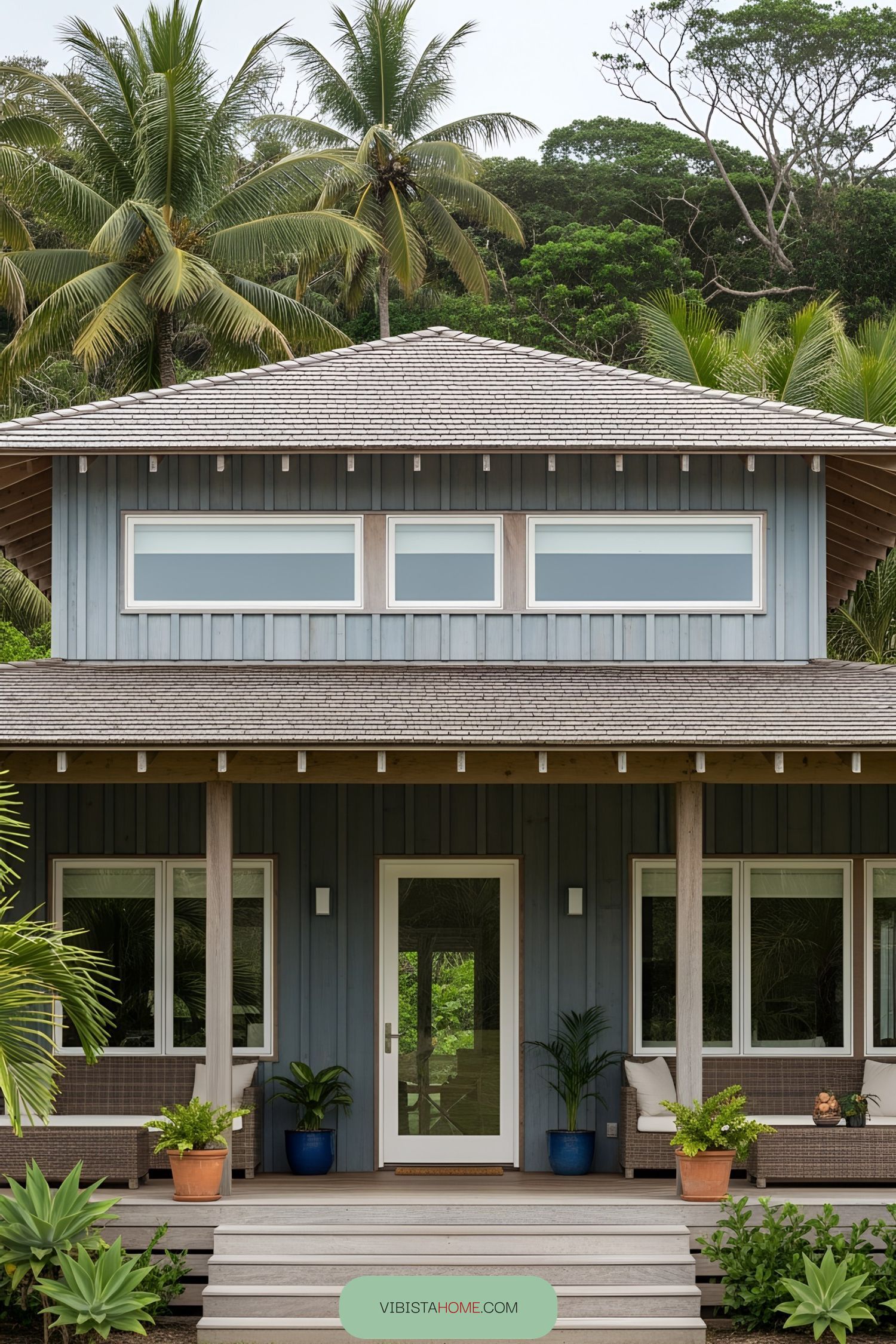 Blue rustic beach house with a porch and palm trees